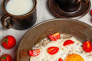 Delicious breakfast with fried eggs and cherry tomatoes in a pan, a Food & Drink Photo by Antonio Gravante Market