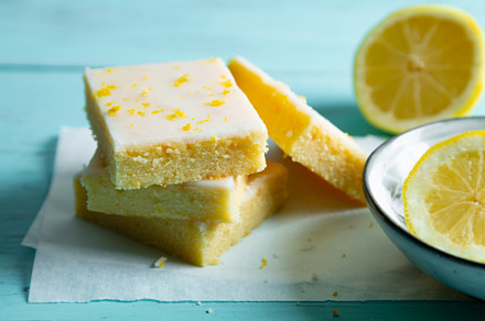 Fudgy lemon brownies with lemon glaze on an aquamarine backgroun