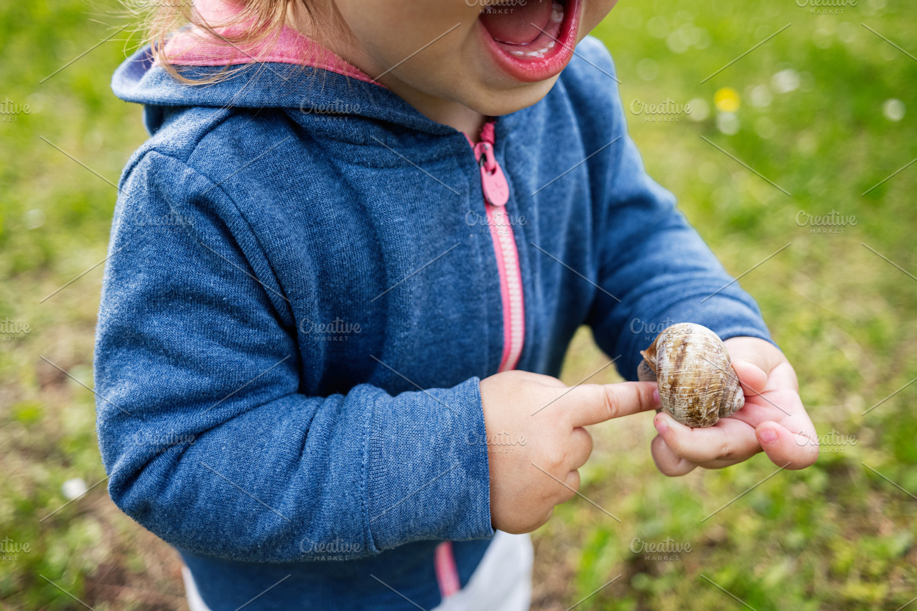 Child exploring nature by holding a snail and pointing with interest, a Person Photo by AS photostudio