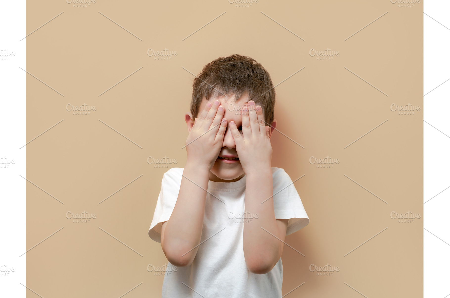 Little boy peeks through fingers of, a Person Photo by Fascinadora