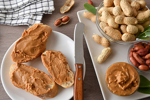 Sliced bread spread with peanut butter on table and nuts, a Food & Drink Photo by Davizro's Market