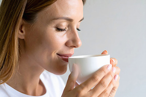 Woman holding tea cup with relaxed and serene smile, a Person Photo by GoodGoods