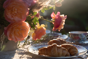 Croissants and tea on a garden table during a peaceful morning b, a Photo by Studio ANNA