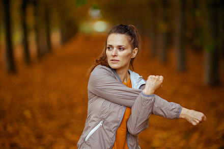 trendy woman in fitness clothes in park stretching, a Sports & Recreation Photo by Alliance Images