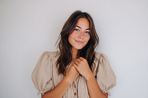 Portrait of a woman smiling warmly against a neutral background in a casual set, a Photo by AlyaAnd