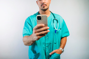 Doctor Using Smartphone in Scrubs, a Person Photo by karrastock
