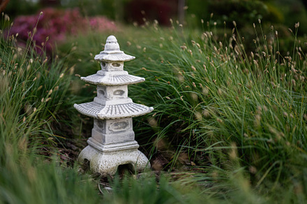 Serene stone pagoda sculpture amidst a lush garden landscape, a Photo by AS photostudio