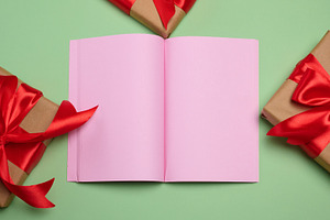 An open notebook with blank pink pages, centered, surrounded by, a Holiday Photo by ndanko