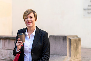 Businesswoman holding coffee in urban setting, a Photo by RF Images