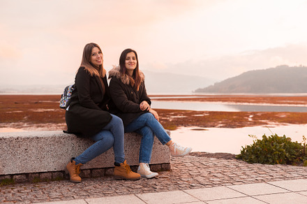 Two female friends sitting on a bench, a Person Photo by rubenchase