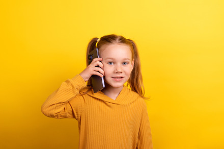 Young girl with pigtails and mustard sweater smiling while talki