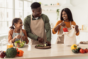 Cheerful Black Family Cooking Making Vegetable Salad In Modern Kitchen, a Photo by Prostock-Studio