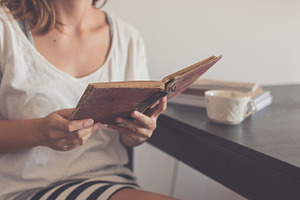Young woman reading an old book featuring holidays, summertime, and reading