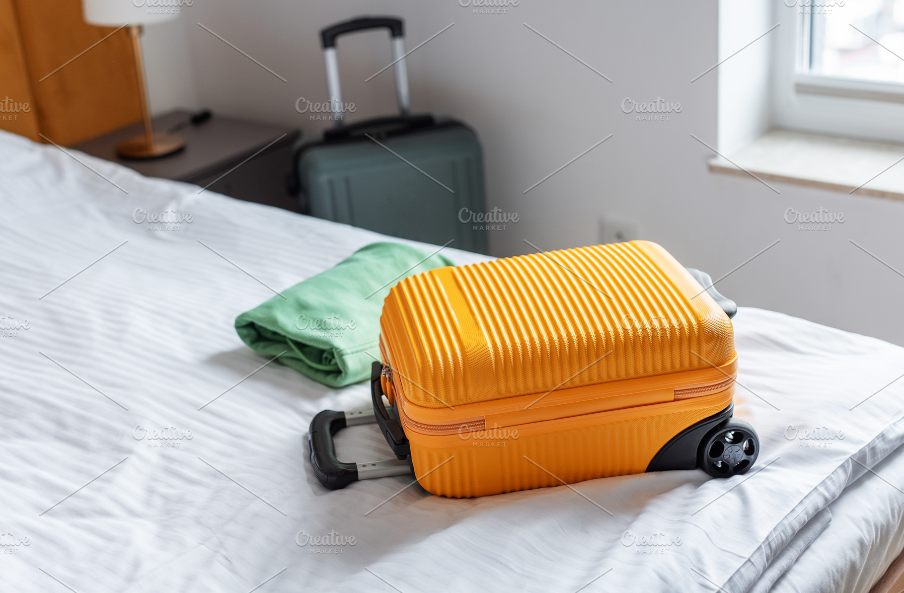 Orange suitcase and folded clothes resting on hotel bed, a Holiday Photo by Olena Rudo