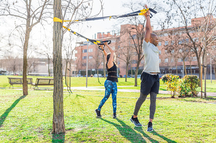 Fitness couple exercising with arms up and rotating the body with trx fitness s, a Sports & Recreation Photo by Iván Moreno STOCK PHOTO