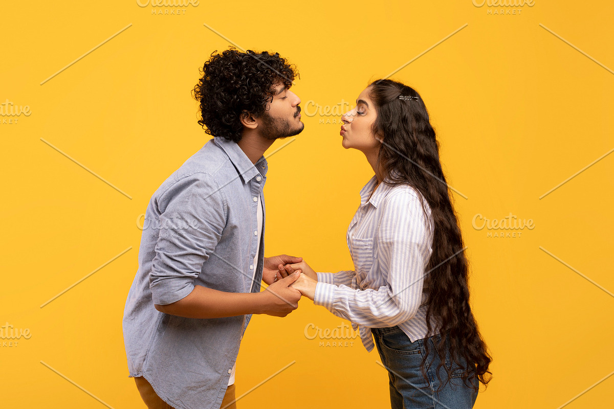 Young indian couple reaching each other with lips, ready to kiss over yellow ba, a Photo by Prostock-Studio (Photo 2 of 4)