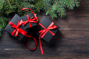 Black christmas gift box with red ribbon and fir branches