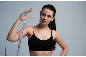 Young woman measuring her body with, a Sports & Recreation Photo by volodymyrshtun13795