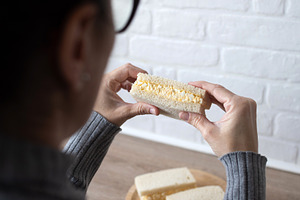 Woman taking a tamago Sando sandwich, a Photo by etorres69