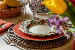 Dining table set with floral patterned plate, elegant glassware,, a Photo by Studio ANNA