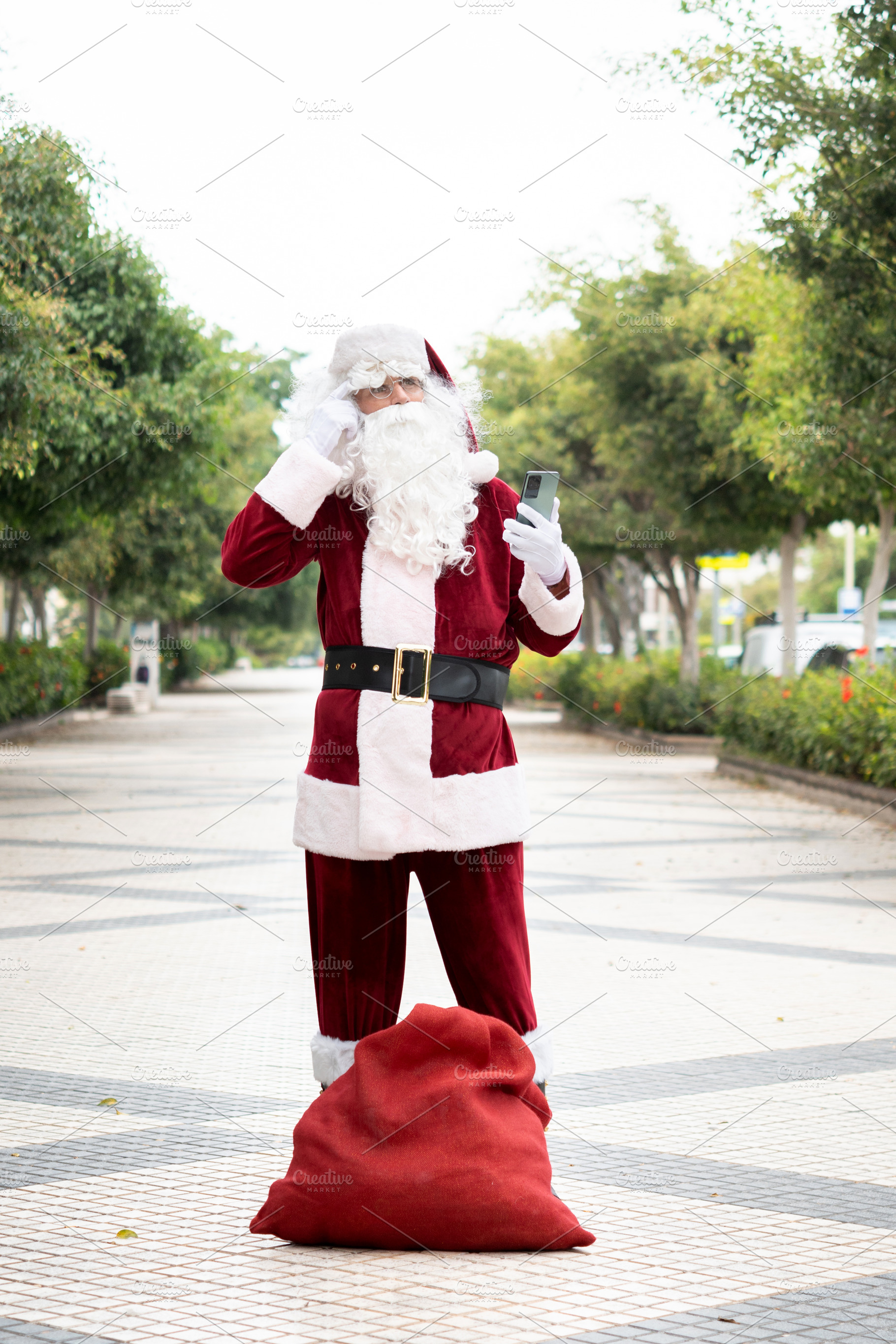 Lost Santa Claus checking smartphone for directions beside gift sack, a Person Photo by etorres69