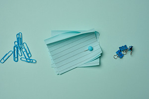 Blue stationery supplies a stack of sheets, paper clips, and pus, a Business Photo by ndanko