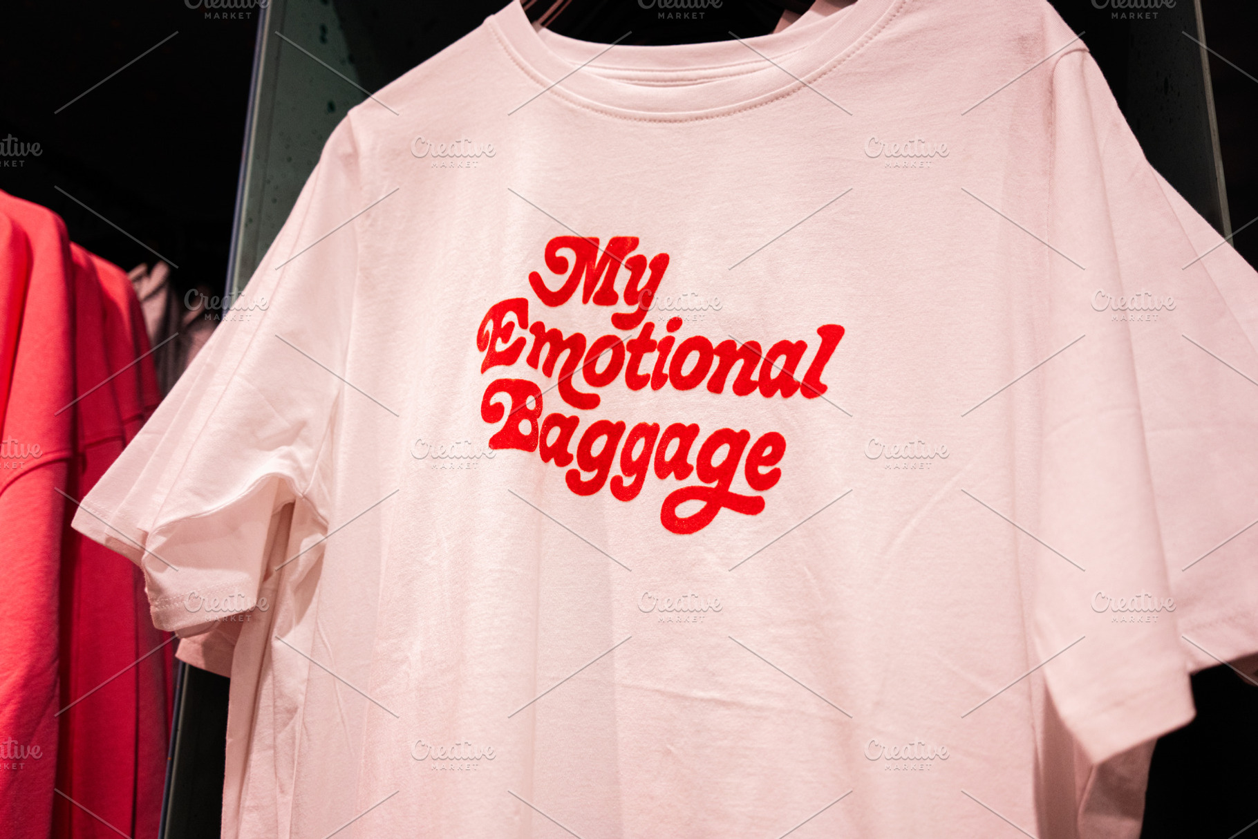 My emotional baggage. White T-shirt with bold red text on display in a clothing, a Photo by AS photostudio