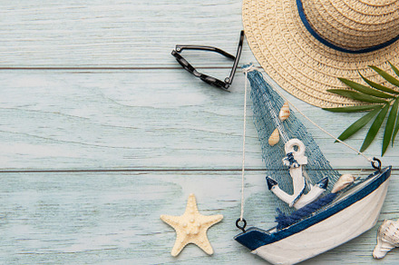 Seashells, sunglasses, straw hat, starfish and decorative sailbo