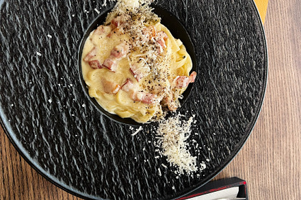 Delicious pasta carbonara served on a stylish plate with utensils on the side, a Photo by AS photostudio