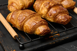 Freshly baked croissants on a black table, delicious breakfast, a Food & Drink Photo by ndanko