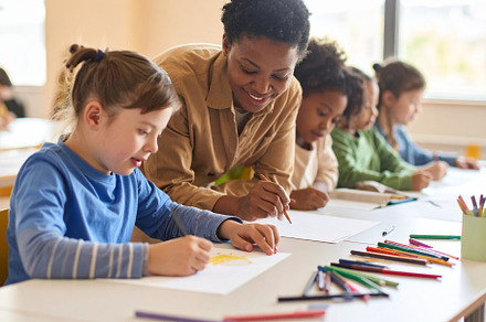 Young teacher with down syndrome girl at classroom