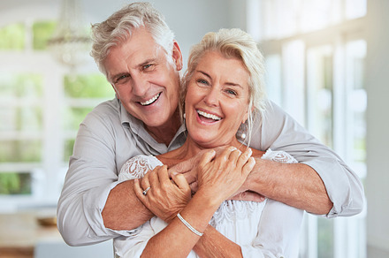 Love, couple and retirement with a senior man and woman looking happy and hugging in their home together. Smile, romance and relationship with an elderly male and female pensioner in a house, a Photo by Peopleimages.com