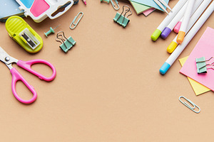 Colorful school and office supplies border on brown background, a School & Education Photo by Olena Rudo
