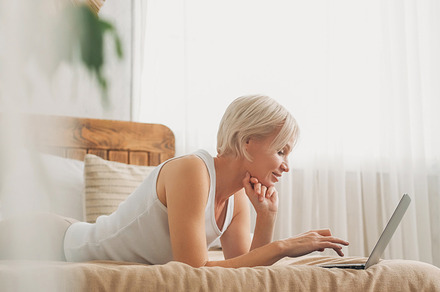 Laptop communication woman typing laying bed home, a Person Photo by Photo Drive Studio