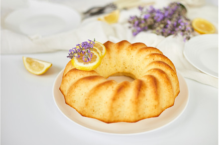Round lemon cake on white table with, a Food & Drink Photo by IlliaBondarPhotography
