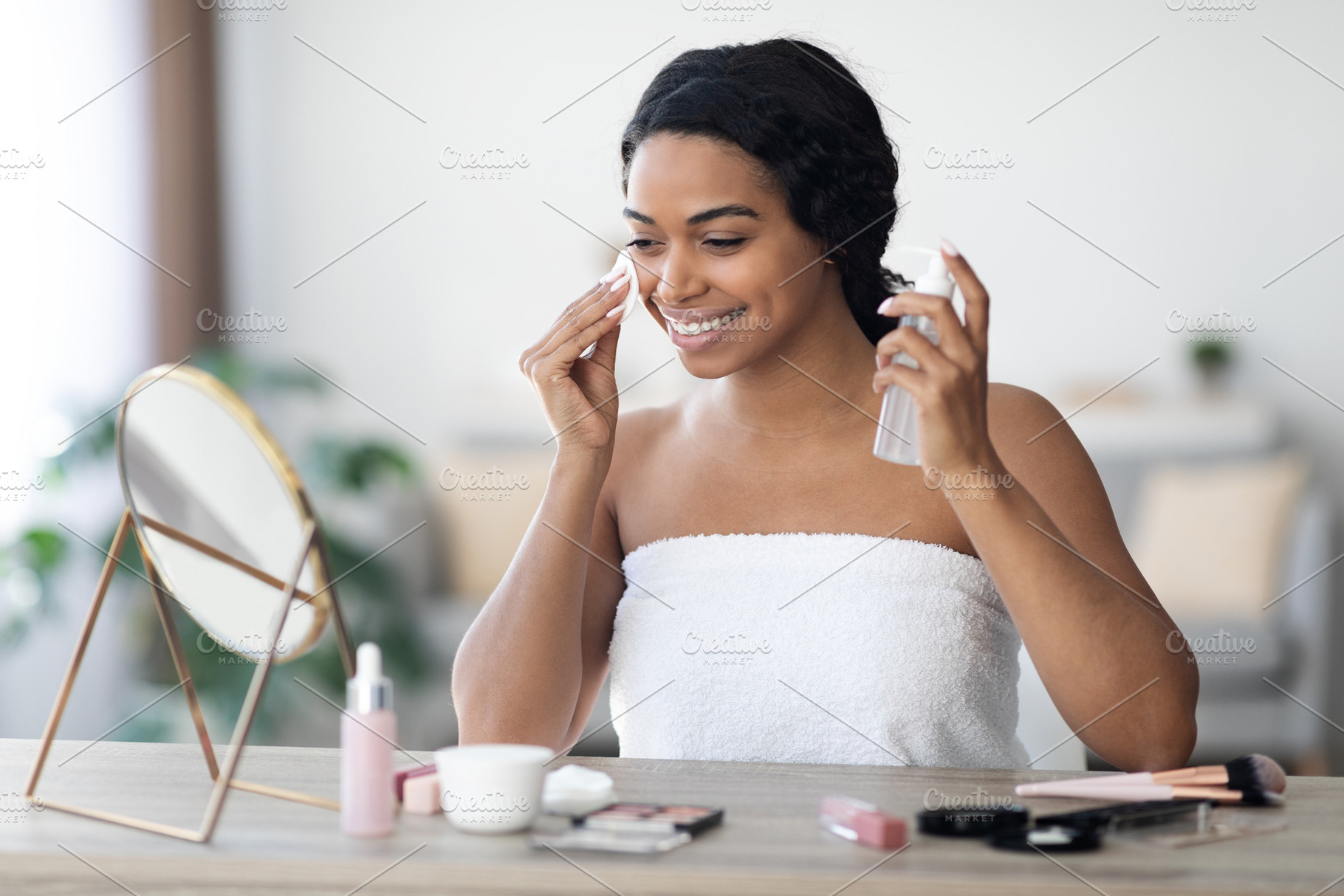 Smiling beautiful african american woman cleansing face, a Photo by Prostock-Studio