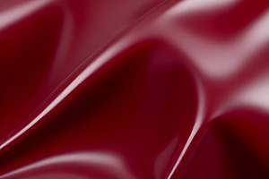 A close-up of deep red glossy leather fabric with soft, flowing folds illuminat, a Background Photo by Kzara Visual Concepts