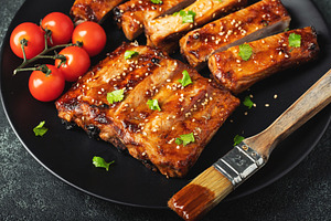Hot grilled spare ribs from a summer BBQ served on a plate with sauce. Top view, a Food & Drink Photo by Budarinphoto
