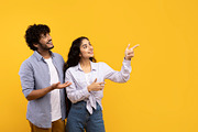 Excited indian couple cheerfully pointing aside at empty space, yellow studio b, a Photo by Prostock-Studio (Thumbnail 2 of 2)