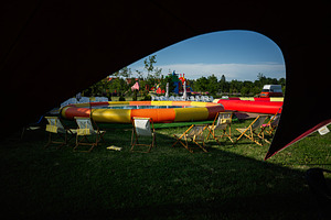 Colorful inflatable structure outdoors surrounded by chairs on green grass, a Photo by AS photostudio