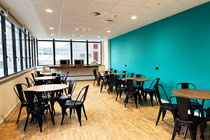 Bright breakroom in Manchester UK featuring teal wall, round tables, and black, a Photo by AS photostudio