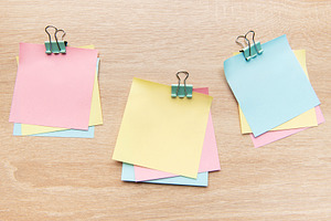 Colorful sticky notes and binder clips on wooden desk