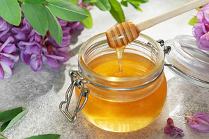Acacia honey in glass jar with wooden dipper, a Food & Drink Photo by Olena Rudo