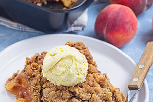 Delicious Peach Crisp or cobbler on plate with scoop of vanilla ice cream, vert, a Food & Drink Photo by iuliia_n