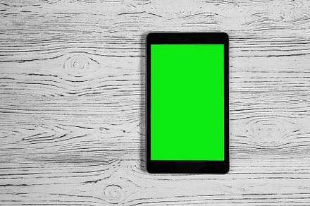 Black tablet with green screen on a wooden table mock up. Copy s, an Abstract Photo by Eugene_Photo