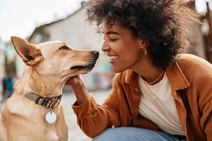 Joyful woman interacting with her dog outdoors, a Person Photo by AlyaAnd