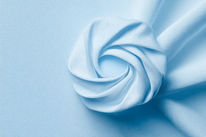 Pastel blue fabric swirling creating a delicate rosette shape an, a Photo by Studio ANNA
