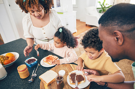 Love, lunch food and black family children, mother and father eating meal, bonding and prepare ingredients. Morning breakfast, kitchen counter or hungry mom, dad and young youth kids excited at home, a Photo by Peopleimages.com