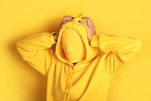 Anonymous individual in a yellow hoodie blends into a seamless y, a Person Photo by Ales Munt