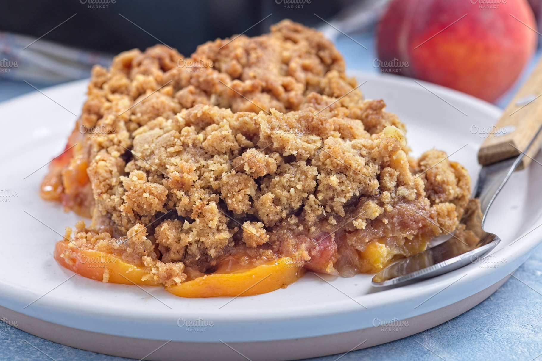Delicious Peach Crisp or cobbler with brown sugar and oat streusel on plate, ho, a Food & Drink Photo by iuliia_n